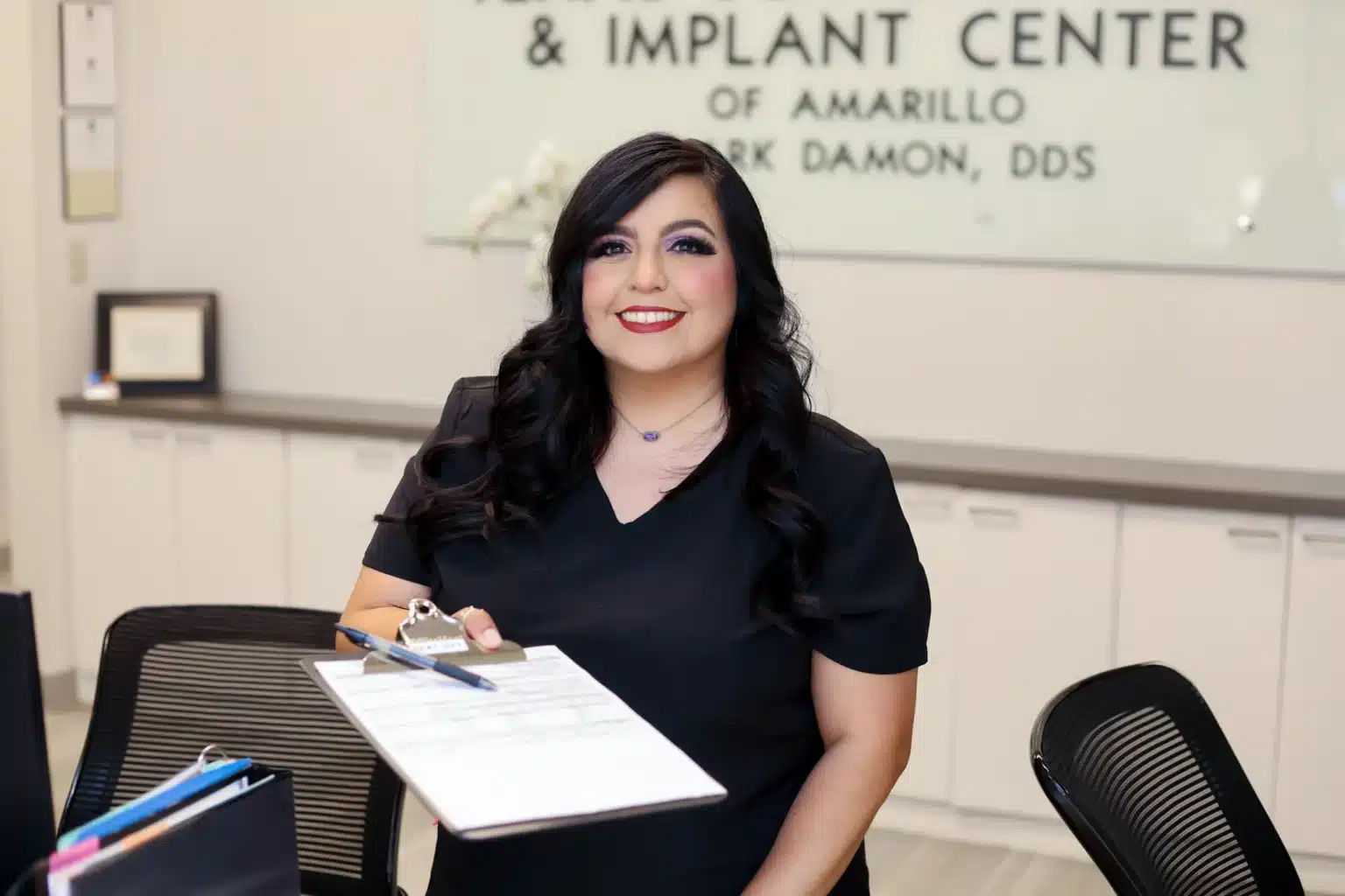 Front desk assistant at our Amarillo dental office holding new patient forms.