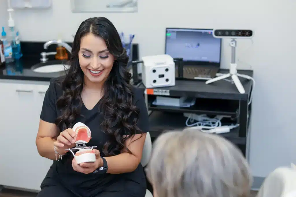 Amarillo dental assistant holding dentures, explaining the procedure to a patient.