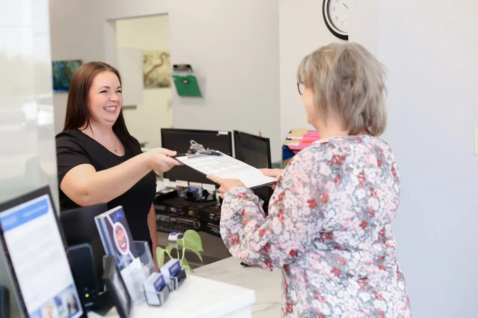 Front desk assistant at our Amarillo dental office giving a patient new patient forms.